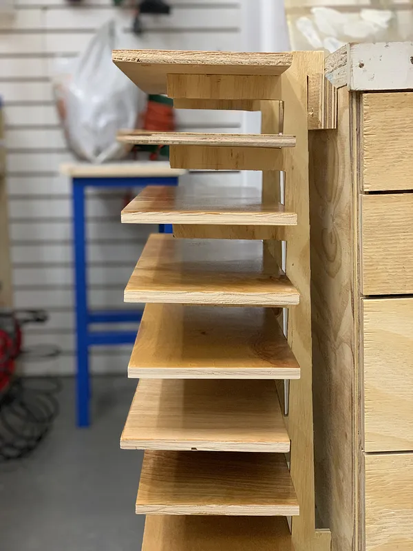 Plywood drying rack mounted on a French cleat wall with boards resting in its slots
